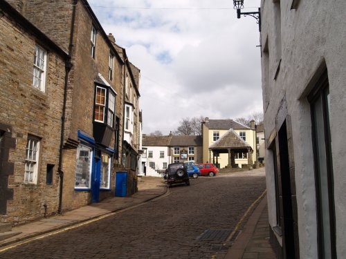 Looking up the cobbled main street to the Market Cross and Market Square.
 Alston Town, Cumbria, North Pennines, Northern England