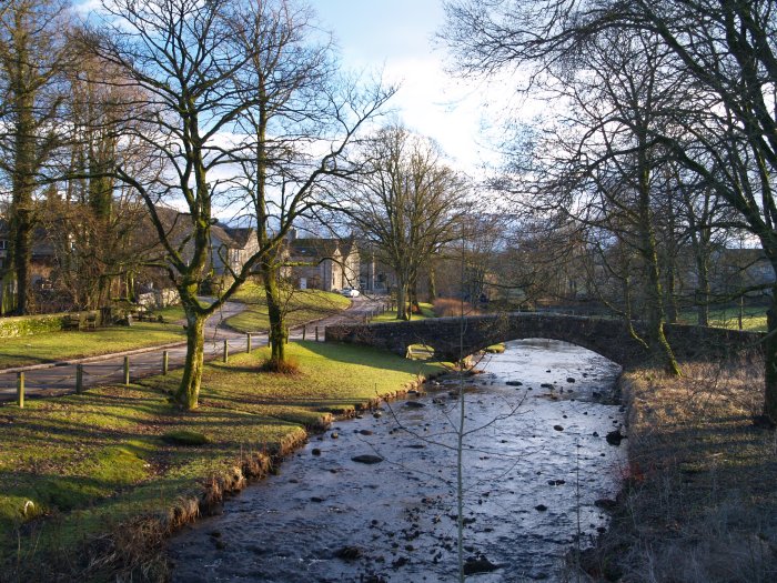 The pretty village green river scene of Linton Beck and the old medieval 14th century packhorse bridge walk from Grassington, Wharfedale, North Yorkshire Dales National Park, England