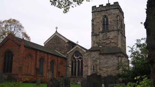 The relatively modern brick chancel? and the stocky' tower of All Saints Church seen from the quiet and peaceful graveyard.