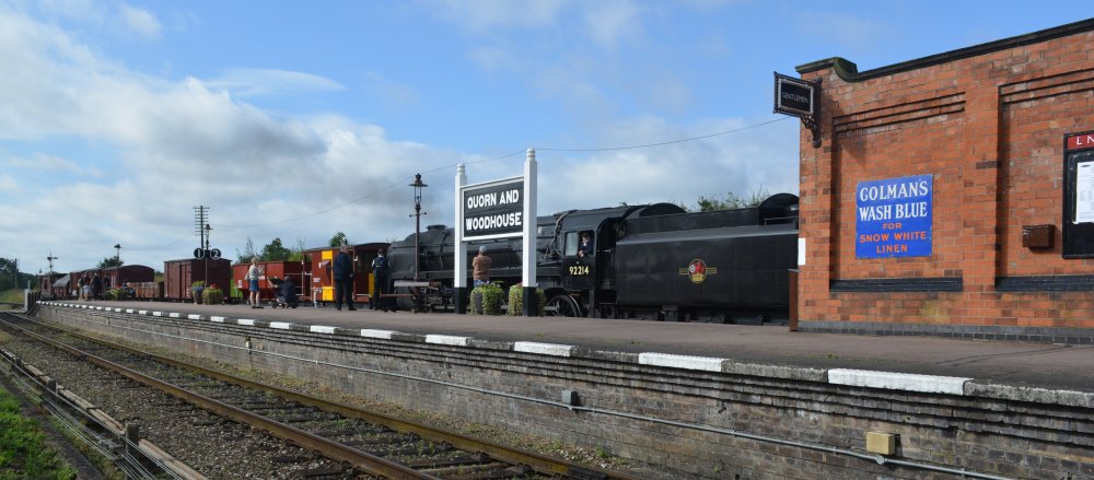 9F 2-10-0 steam locomotive 92214 passing north through Quorn and Woodhouse station with a demonstration freight train, Great Central Railway heritage weekend Gala 'Railways at Work' (GCR August 2023)