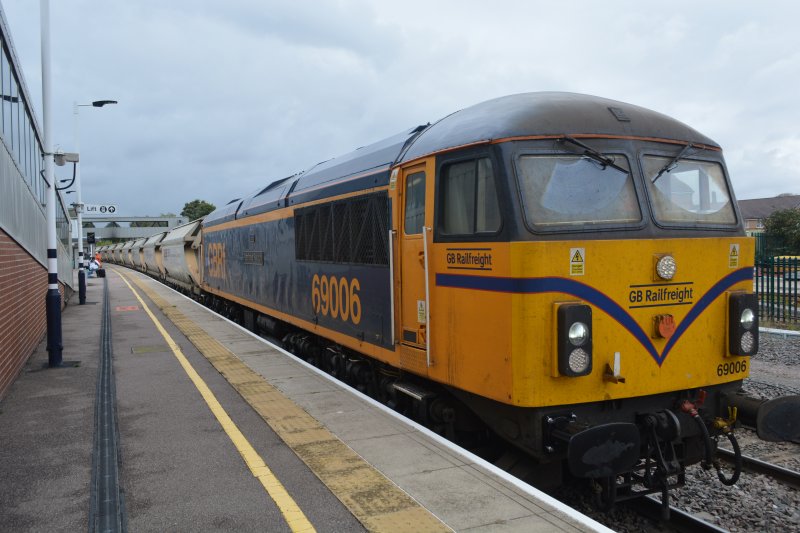 Class 69 Diesel locomotive 69006 Pathfinder Tours (Peter Watts 50 years service 1973-2023), with a rake of hopper wagons of stone, Peterborough station, 2024