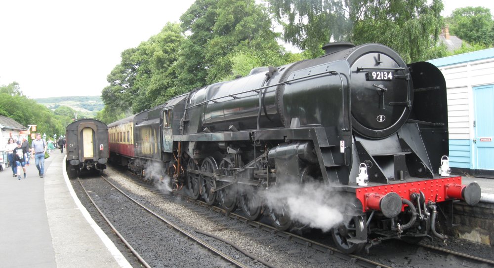 North Yorkshire Moors Railway:  portrait of 9F 2-10-0 freight locomotive 92134 at Grosmont station with an NYMR service to Pickering 92024).